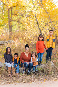A mother poses with her children on a log by Laramee Love Photography