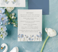 a flat lay of white wedding stationery with blue floral embellishments