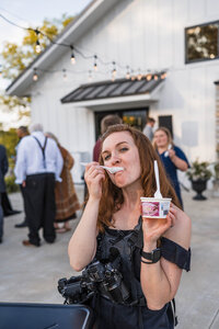 Photographers eats ice cream with camera strapped to her