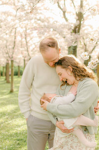 Toddler girl reaches out to her infant baby sister during a family photoshoot in Vondelpark. 