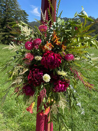 Vibrant floral arrangement with deep red and pink tones on an outdoor arch