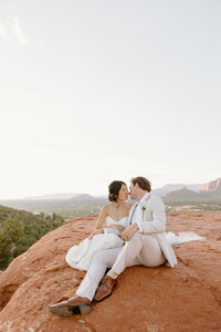 Wedding couple kisses on rock in Sedona’s desert light.