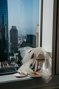 Bridal shoes and bouquet placed on a window ledge with San Francisco skyline views, styled and photographed by San Francisco elopement photographer Kristin Smith.