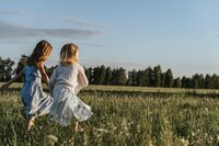 Two young girls running in a grassy field | playful childhood moments supported through evaluations and guidance