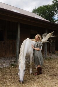 Woman connecting with her horse outside a wooden barn during an equine-assisted support session for horse owners in the Berkshires