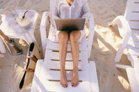 Overhead photo of girl working on her laptop on a beach lounger on the sand