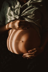 A person holding their pregnant stomach