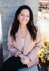 Alison Seponara in a pink blazer with a grey brick background