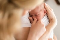 A woman holds and comforts a newborn baby.