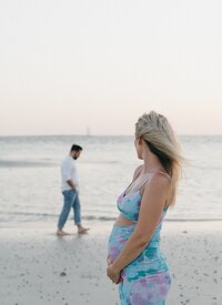 Pregnant woman with spouse on beach taken by florida engagement photographers Shelby Ann Photos