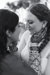 A newlywed couple leaning in for a kiss with their hands on each other's faces 