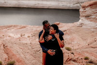 A couple sharing a tender engagement moment on a boat in the clear blue waters of Lake Powell, with stunning cliffs in the distance.