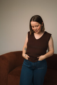 Liv Rollings posing by rust colored couch