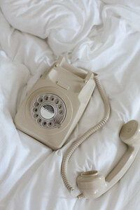 Retro corded telephone sitting on a bed