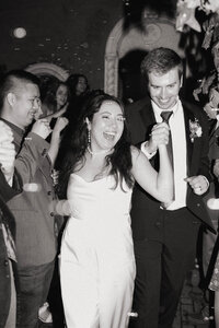 Bride and groom smiling and celebrating as they exit their wedding reception, surrounded by guests, captured by a Spokane photographer.