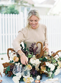 A woman setting a flower bouquet on a table.