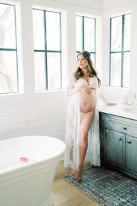 a mother stands in her bathroom during an intimate maternity session