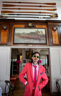 Grooms men posing infront of Thames Rowing Club sign wearing neon pink suit at a Thames rowing club wedding reception