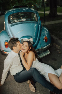 couple sits behind VW beetle