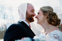 Bride and groom about to kiss under a veil