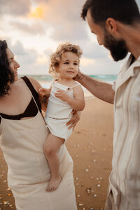 Pregnant woman in jeans with sun beaming behind her.