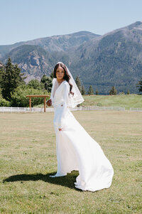 Bride wearing a fingertip length circle veil with blusher and a bold ribbon edge, and holding a white and blush bouquet
