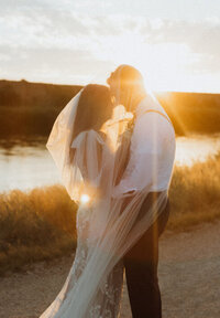 bride and groom under veil at golden hour