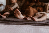 Family of four toes laying in  on a bed during their family session in Denver