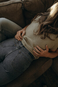 Man rests his hands on his wife's back as she straddles him on the couch