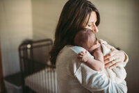 mother cuddles newborn over shoulder