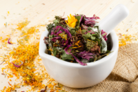 white mortar and pestle filled with purple green and yellow herbs
