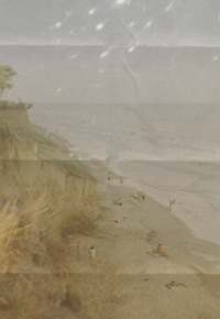 Retro sepia photo from a bird's-eye-view of the shoreline with people laying in the sand.