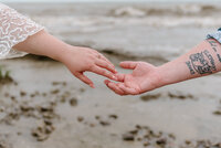 bride and groom hold hands on lake erie shore