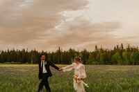 A bride and groom holding hands running slightly towards the left of the camera.