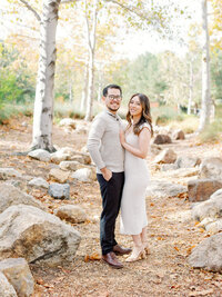 couple posing smiling at the camera during fall engagement session at irvine trail