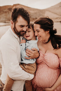 pregnant mom snuggling with husband and toddler