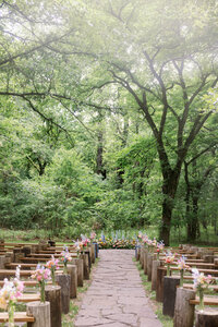 Outdoor Oklahoma wedding ceremony with wooden benches and floral aisle in a lush green garden setting