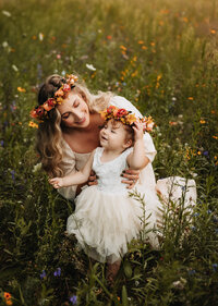 Mother and daughter wearing flower crowns in a Michigan field at sunset.