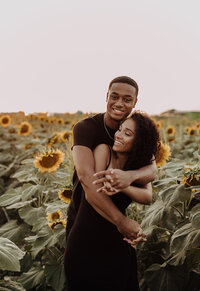Couple embracing each other and laughing in a sunflower field