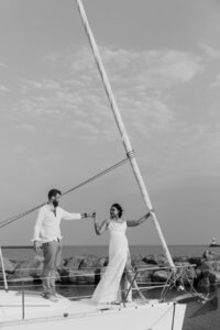 A couple reaching out and holding hands on a sailboat 