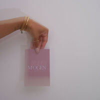 Hand holding M'ogen postcard