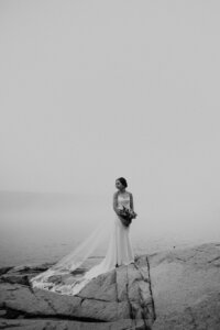 black and white image bride posing on rock