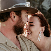 A woman smiling while her chin is on her partner's shoulder. 