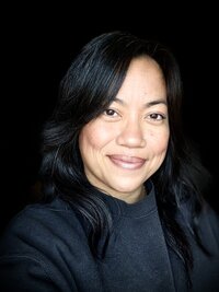 woman with long black hair smiling at the camera and wearing a black shirt