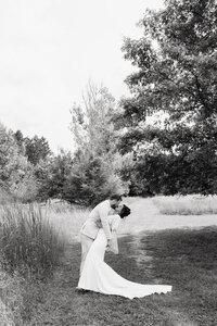 Black and white image of couple kissing in front of the water