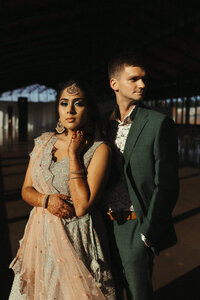 A bride wearing a lehenga and a groom in a suit in the sunlight at their wedding