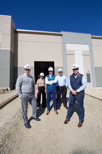 Group of businesspeople in hard hats in front of commercial construction