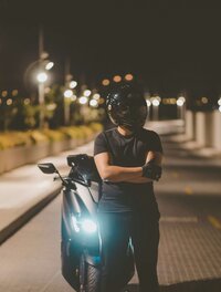 Man posing for photo next to motorcycle