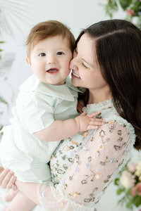 mom smiling while holding baby and baby smiles at camera