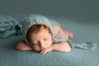 Baby boy posed  on eggshell blue during his baby session.